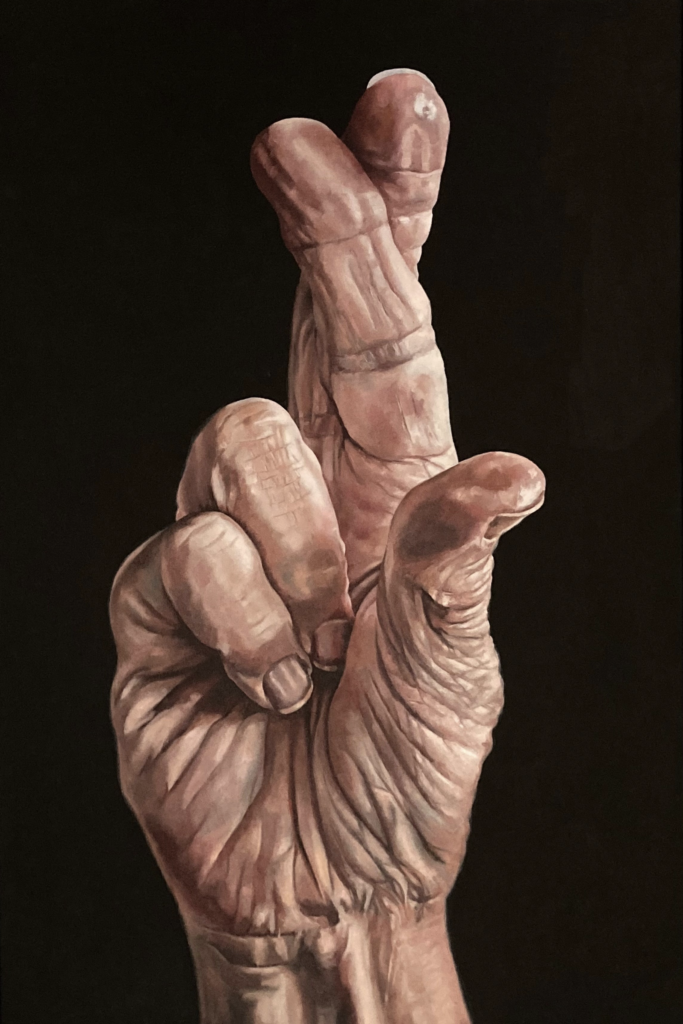 A large painted hand with two crossed fingers against a black background